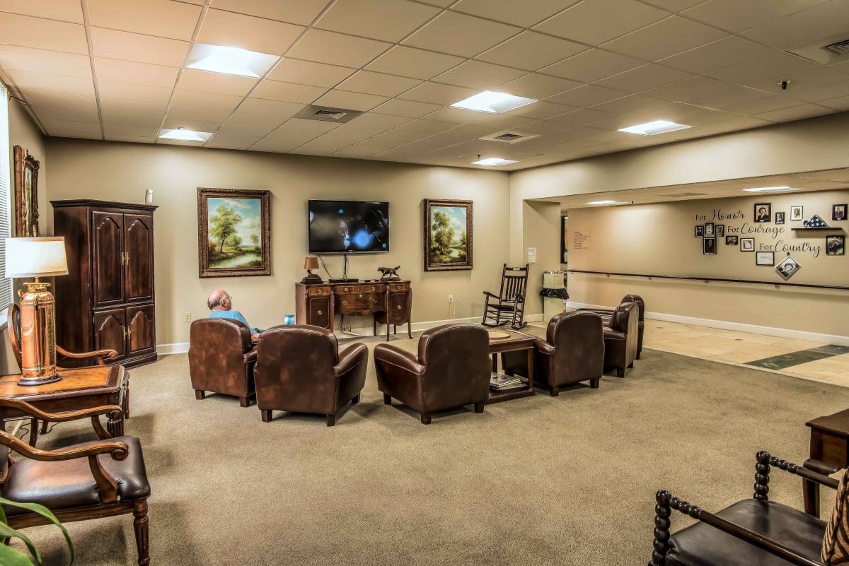 A cozy lounge with leather chairs and large paintings on the walls.