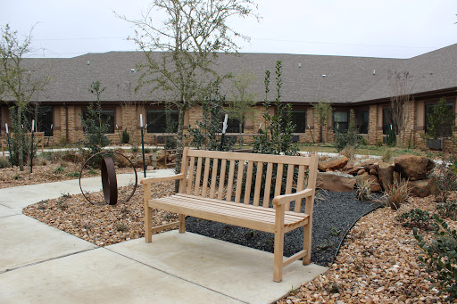 A wooden bench situated in a serene garden setting, surrounded by plants and a walkway.