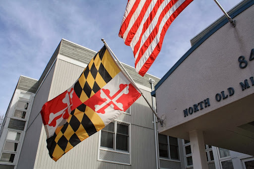 Flags of Maryland and the United States flying together in front of a building.