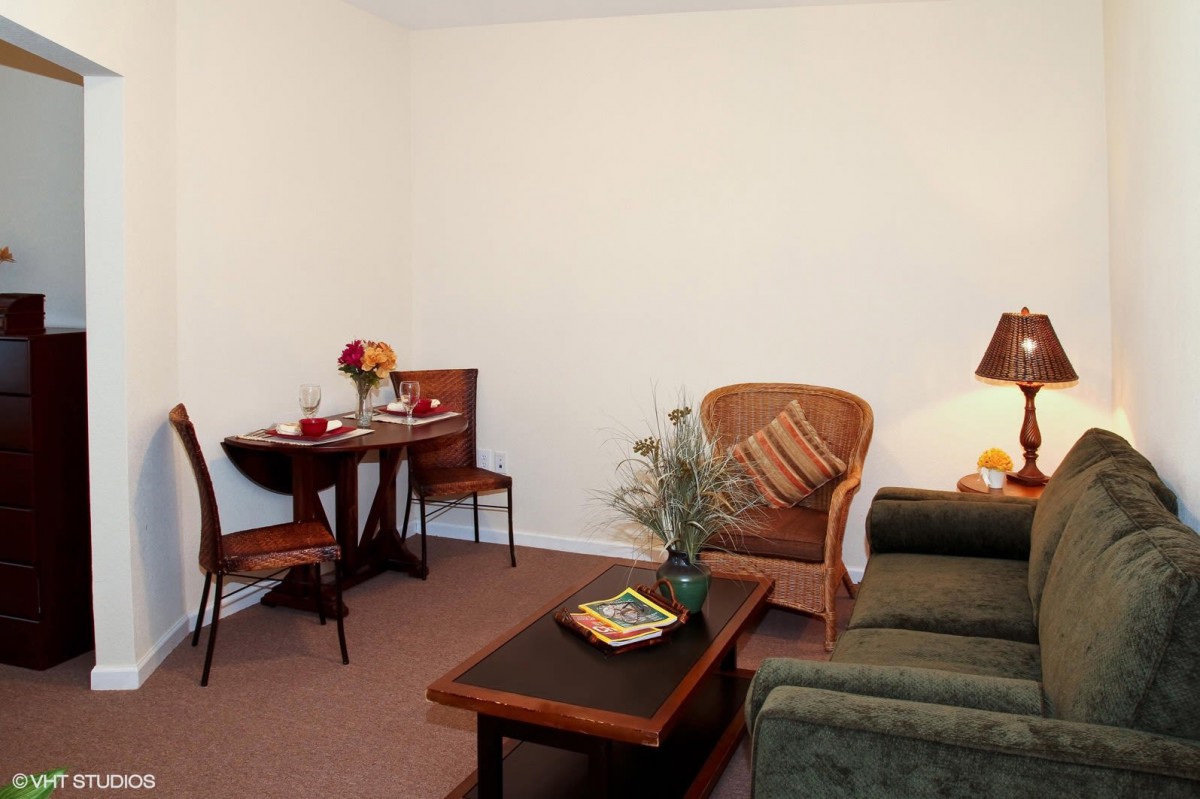 A cozy living room featuring a sofa, coffee table, and a small dining table set.