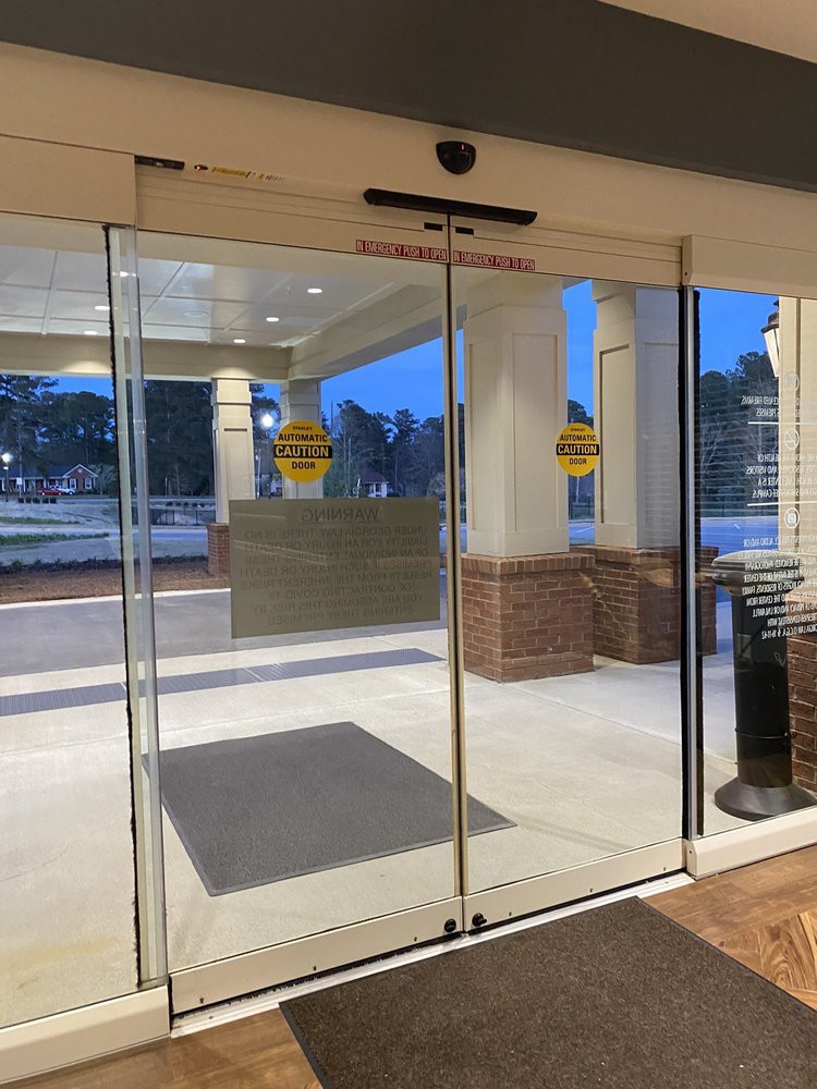 An automatic glass door at a building entrance, with 'No Entry' signs visible.