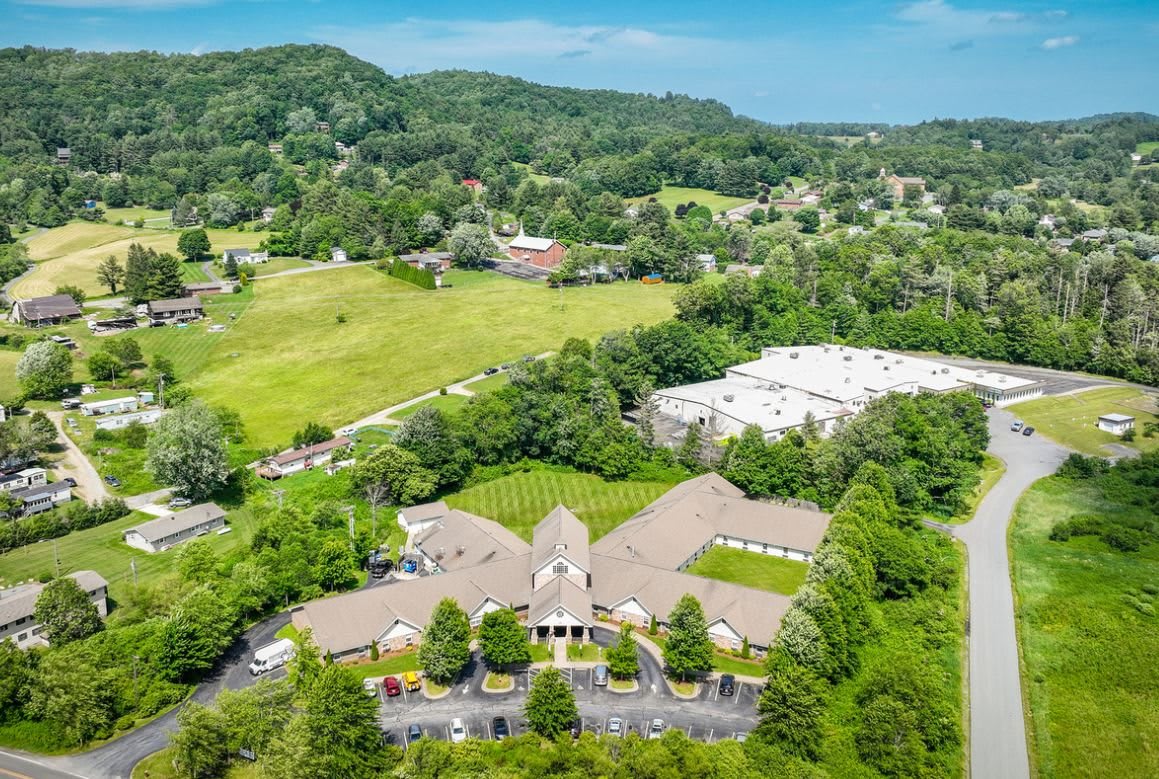 Aerial view of a countryside landscape with buildings surrounded by greenery and hills.