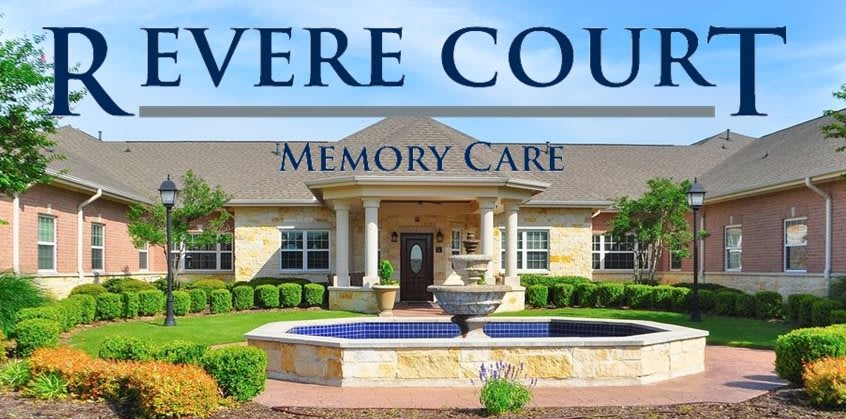 Exterior view of a memory care facility with a central fountain.