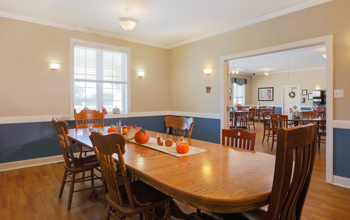 A cozy dining room with autumn-themed decor, featuring a large wooden table and chairs.