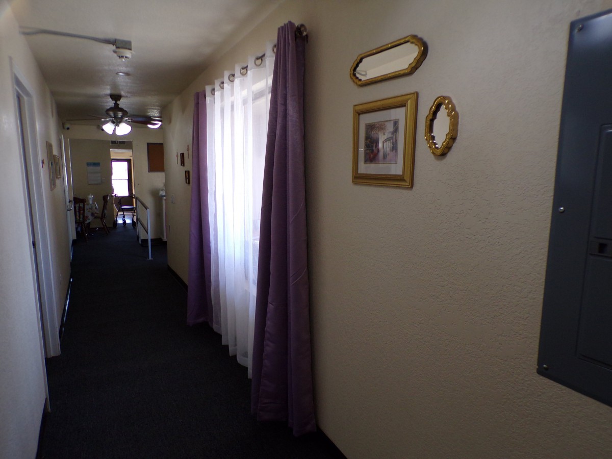 A dimly lit hallway with purple curtains and framed pictures on the wall.