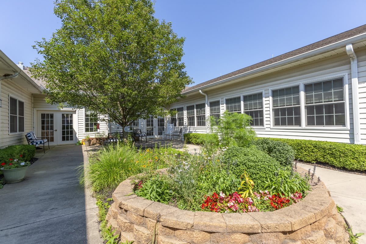 A scenic view of a garden area with lush greenery and a building in the background.