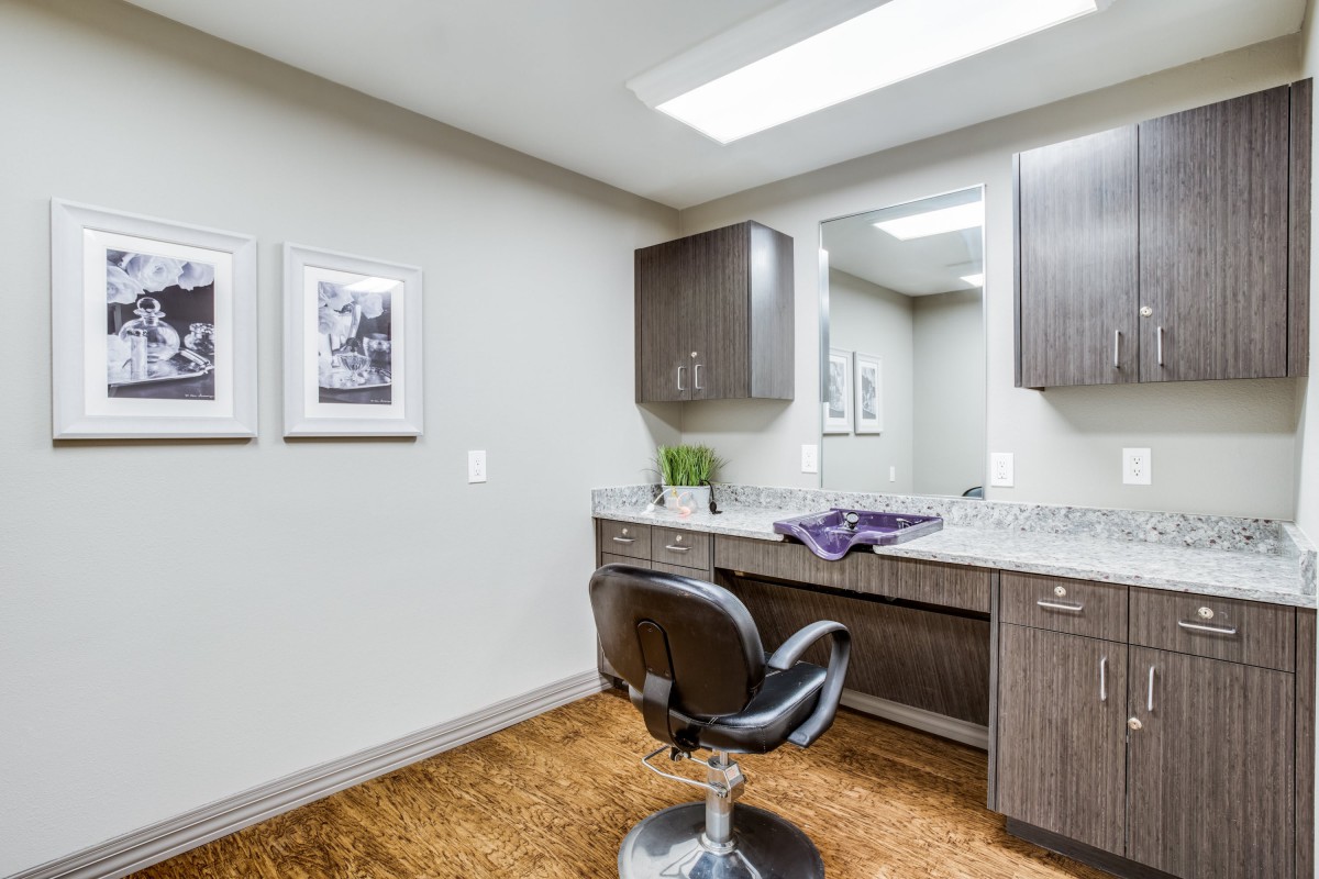 A well-organized hair salon interior featuring a styling chair, mirror, and cabinetry.