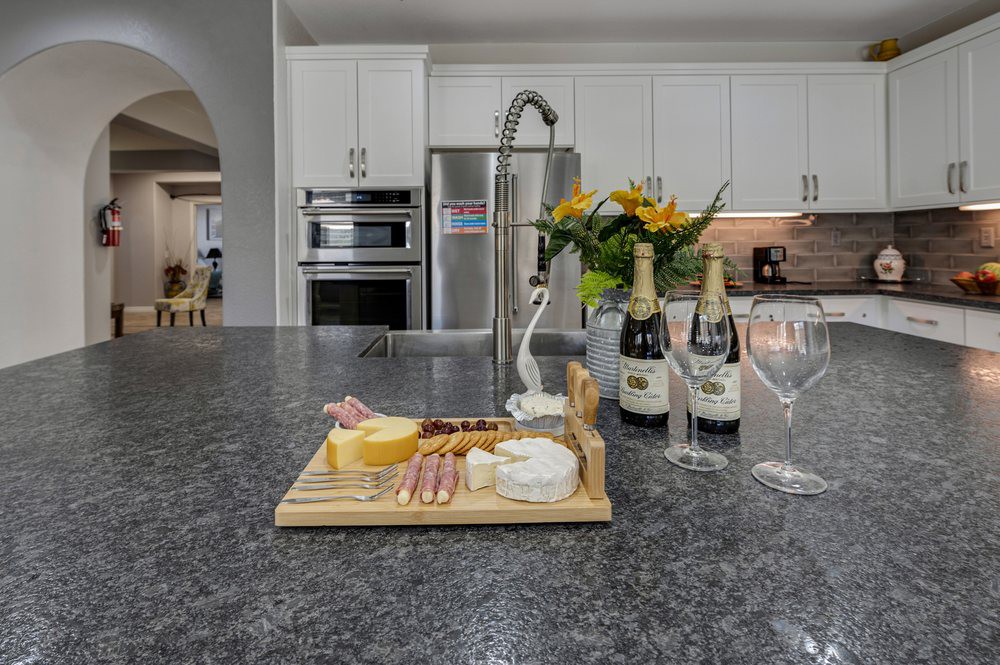 A modern kitchen with a cheese platter and wine bottles on the countertop.