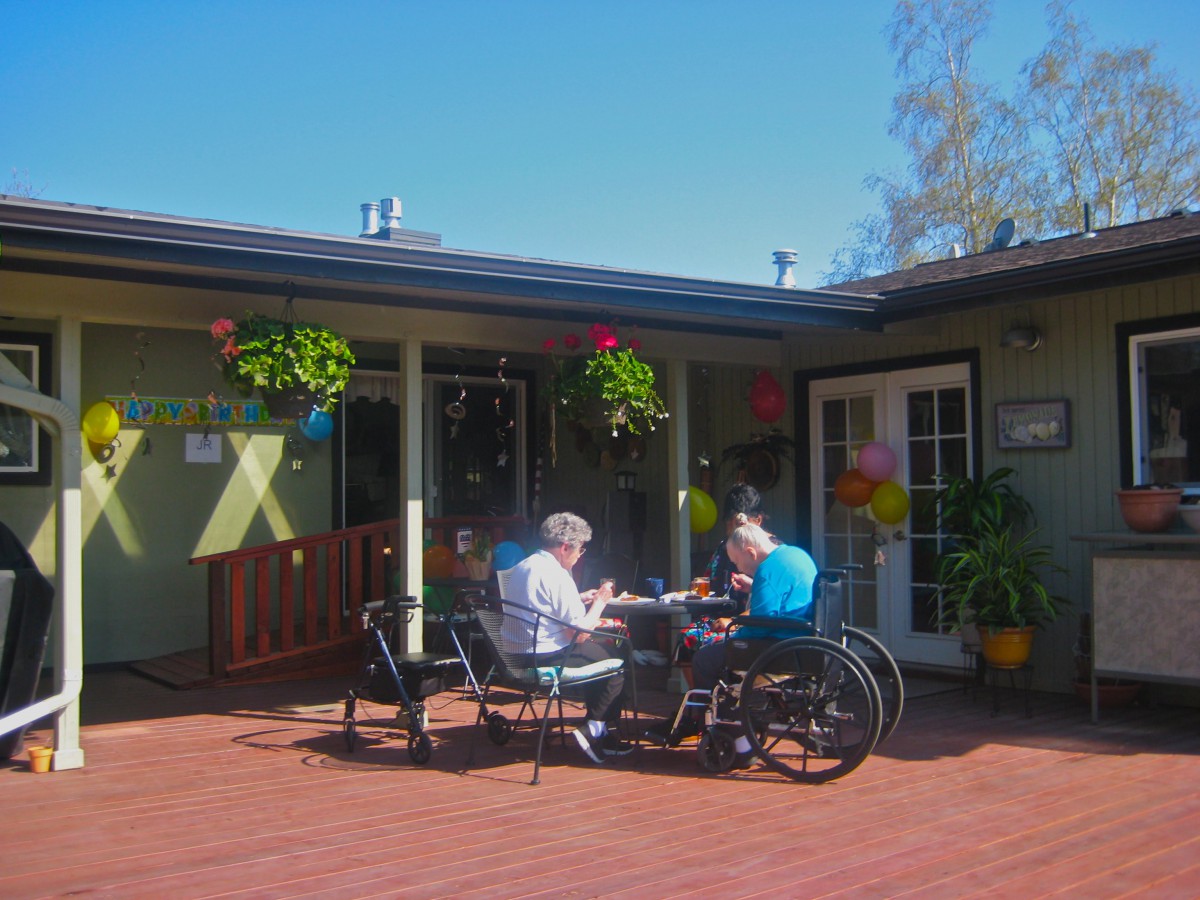 Two people enjoying a conversation at an outdoor patio on a sunny day.