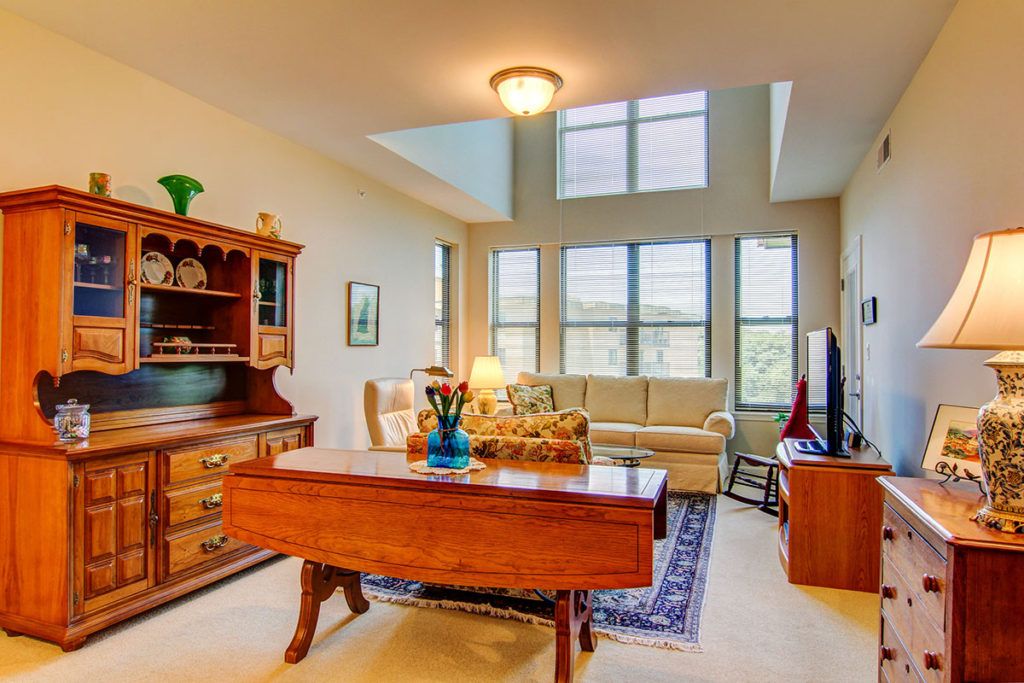 A cozy living room with large windows, featuring a wooden table, comfortable sofa, and elegant decor.