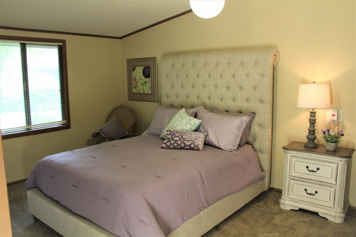 A cozy bedroom with a tufted headboard and lavender bedding.