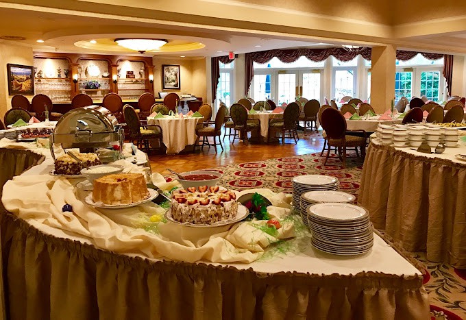 A well-arranged buffet setup in an elegant dining room, featuring a variety of desserts and neatly arranged tables.