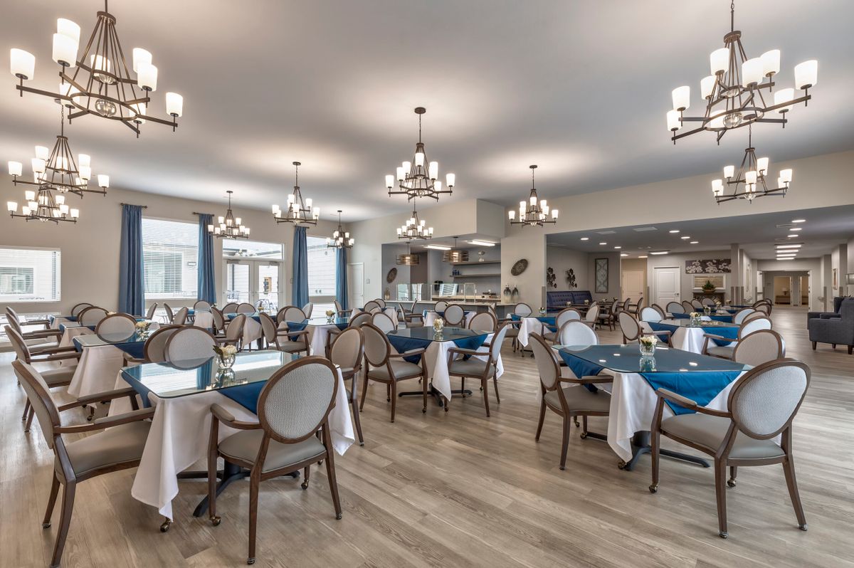 An elegantly designed restaurant dining area with multiple tables and chairs, featuring chandeliers and a warm ambiance.