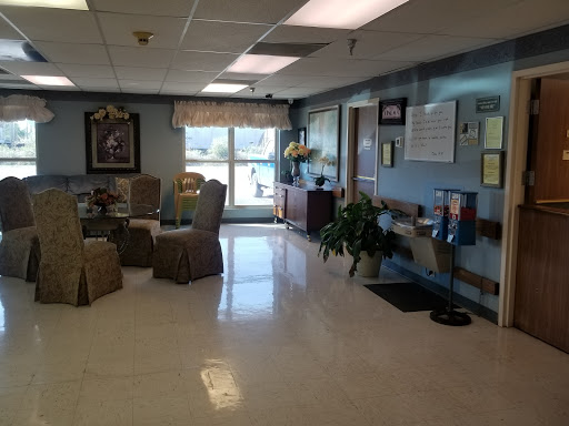A spacious and well-lit waiting area in a healthcare facility, featuring comfortable seating and decorative plants.