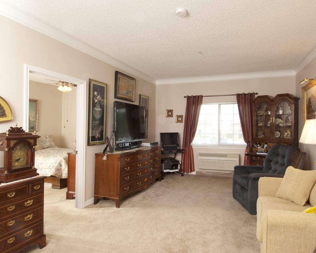 A cozy living room with elegant furnishings, featuring a television and decorated with framed artwork.