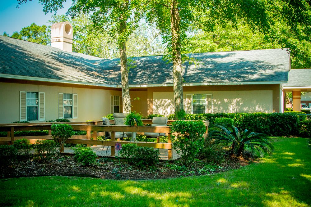 A quaint house with a wooden deck surrounded by lush greenery and trees.