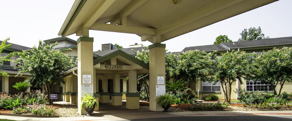 The entrance of a hospital building surrounded by greenery.