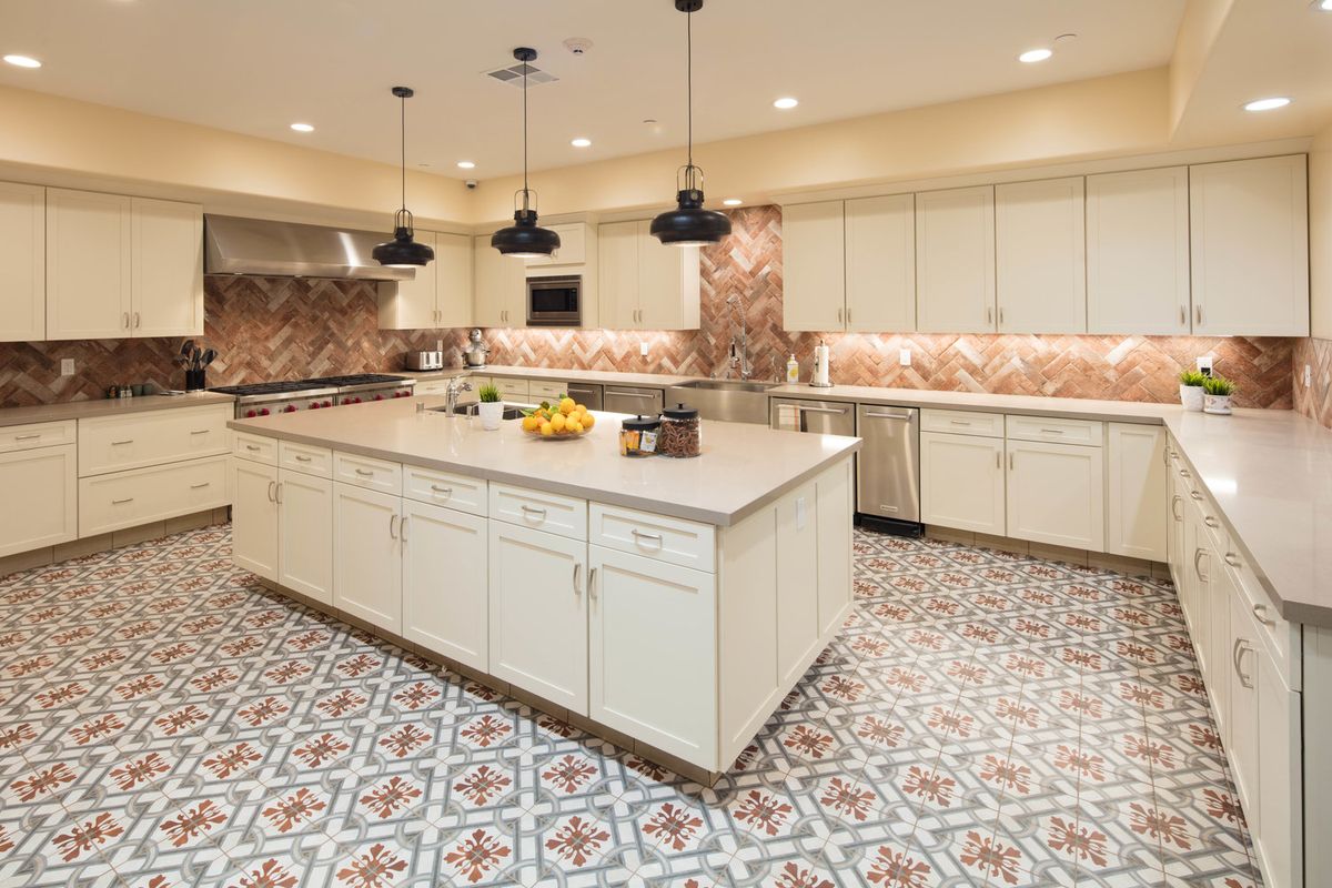 A spacious modern kitchen with an island and decorative tile flooring.