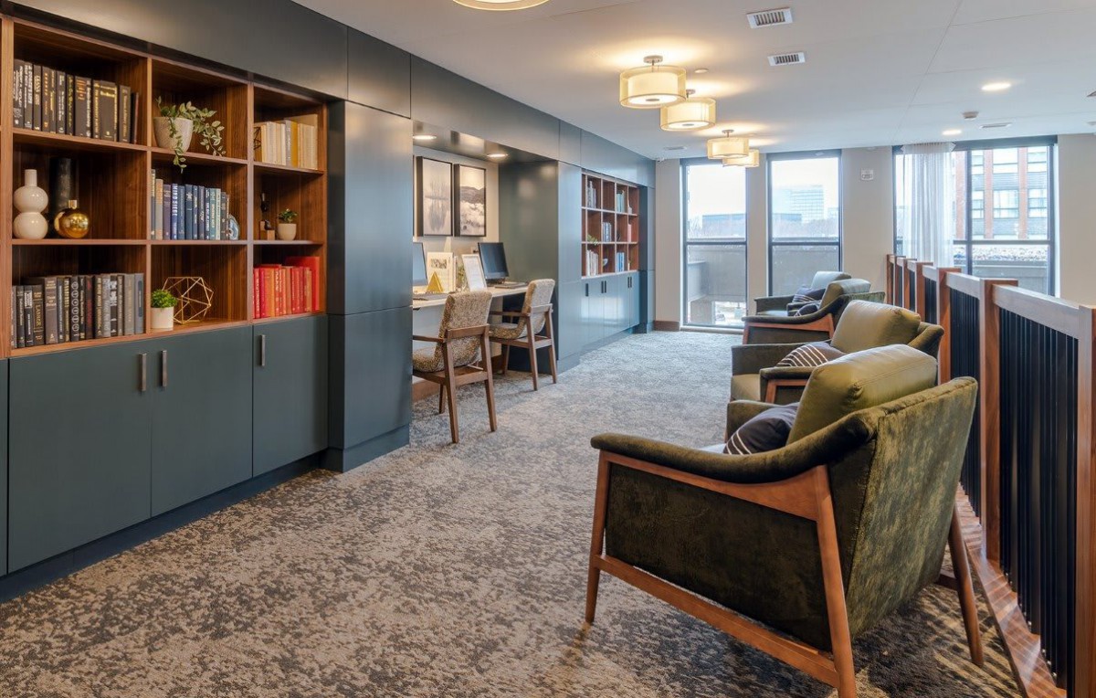 A modern and cozy living room with bookshelves and a workspace area.