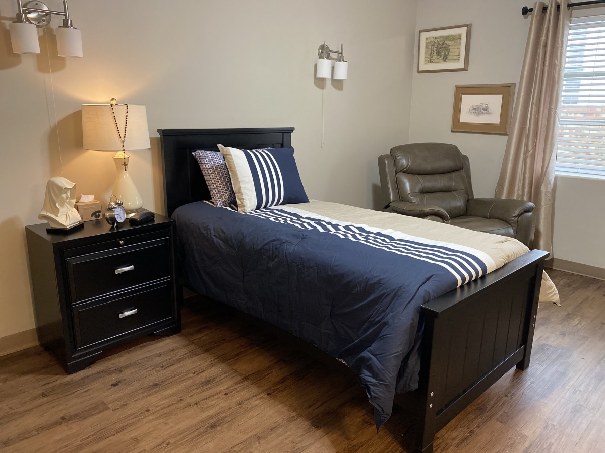 A cozy bedroom with a single bed, nightstand, and armchair.