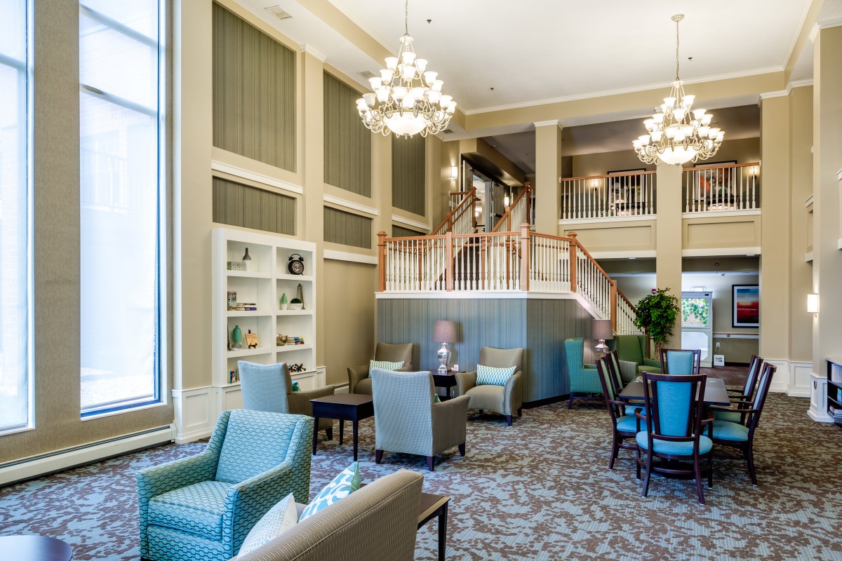 An elegant lobby with comfortable seating, chandeliers, and a staircase.