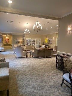 A spacious and elegantly decorated living room with comfortable seating and chandeliers.