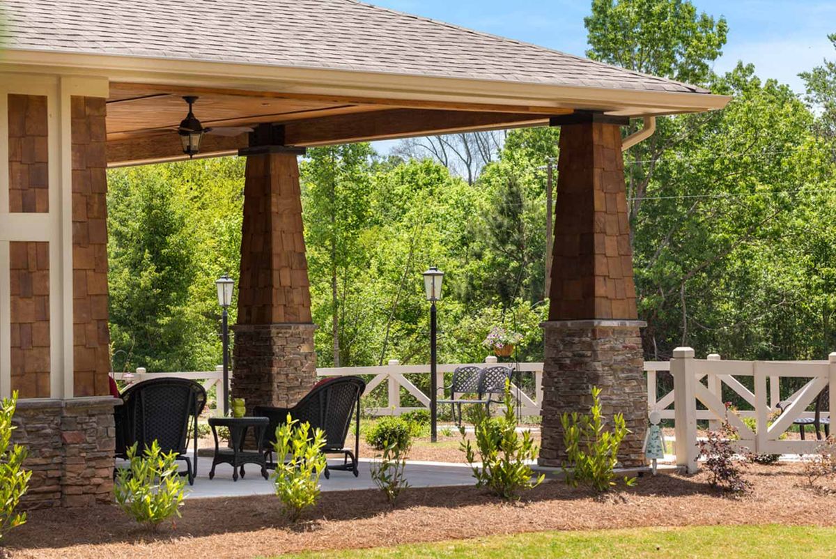A cozy outdoor gazebo with seating surrounded by lush greenery.