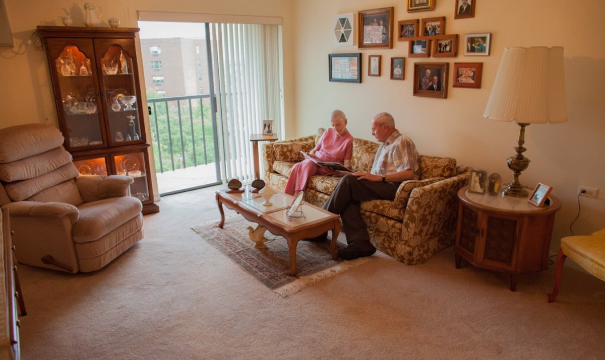 An elderly couple sitting together on a sofa in a cozy living room.