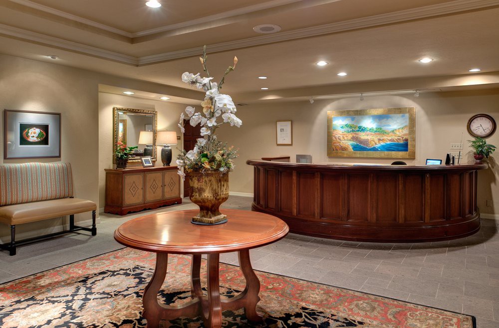 A warmly decorated reception area featuring a wooden table with floral centerpiece and framed artwork on the wall.