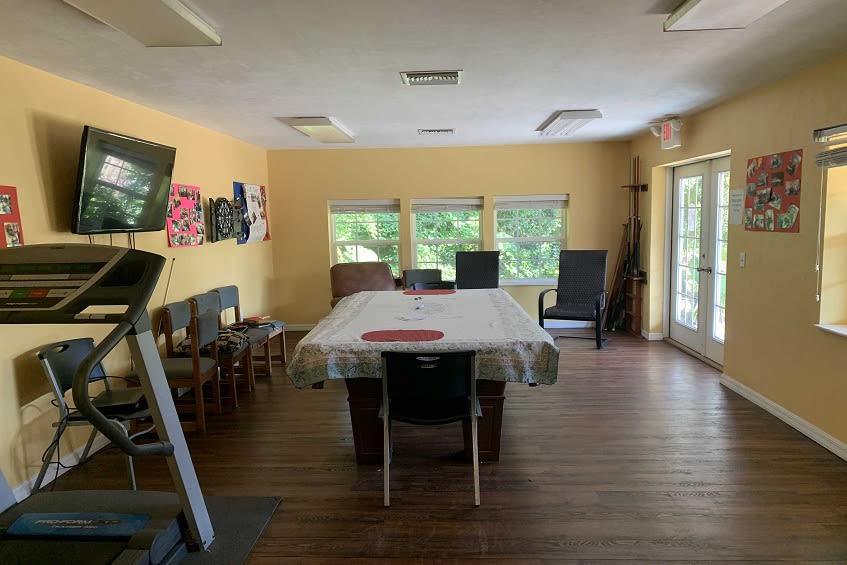 A spacious room with a dining table and chairs, decorated with artwork, featuring large windows that allow natural light to fill the space.