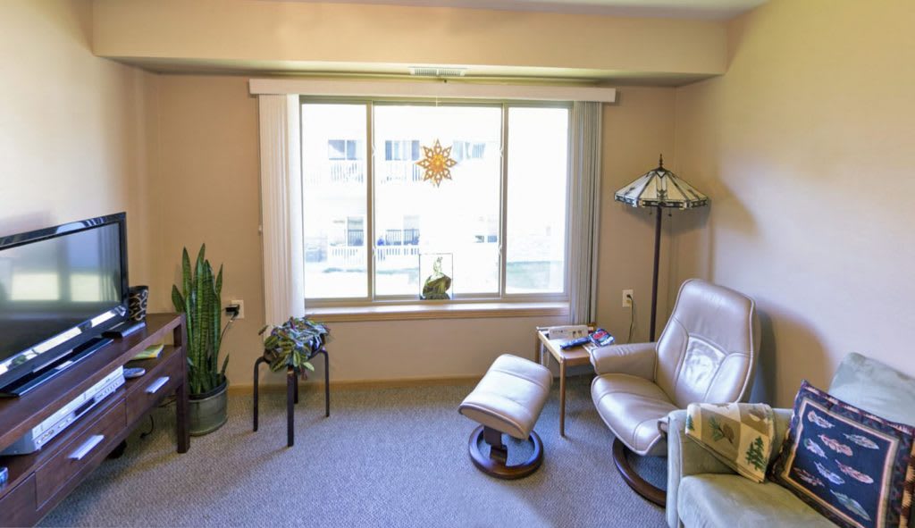 A cozy living room corner with a comfortable chair and ottoman near a large window.
