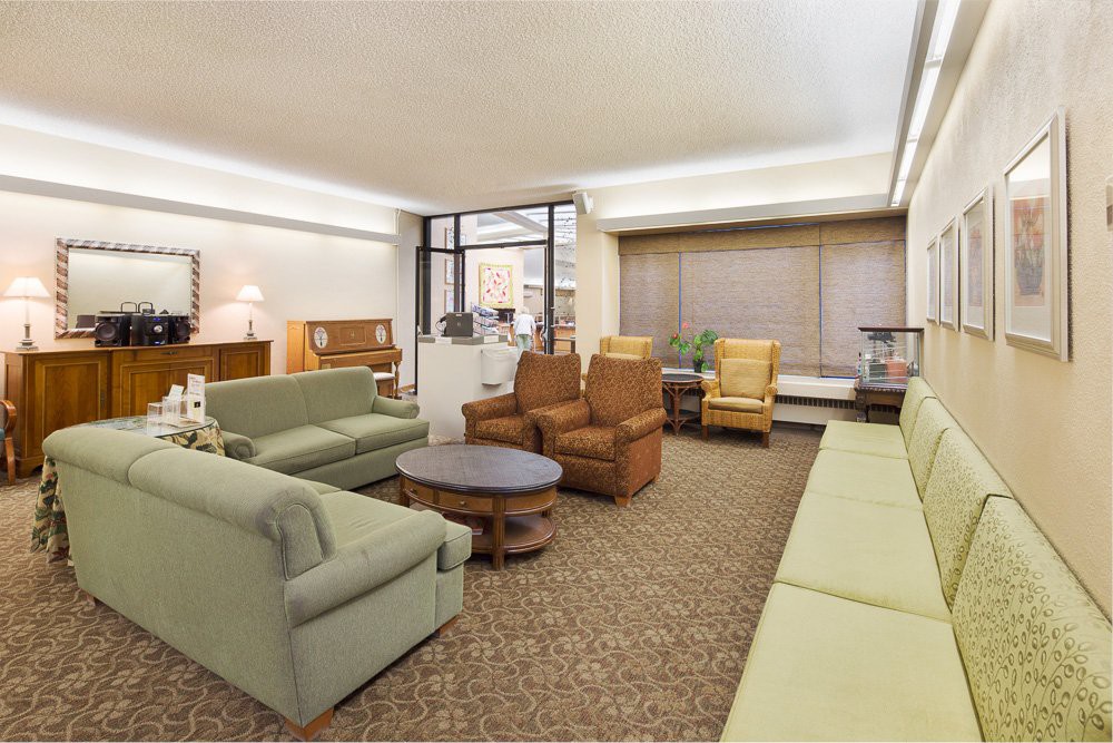 A spacious living room with various seating options and a large window.