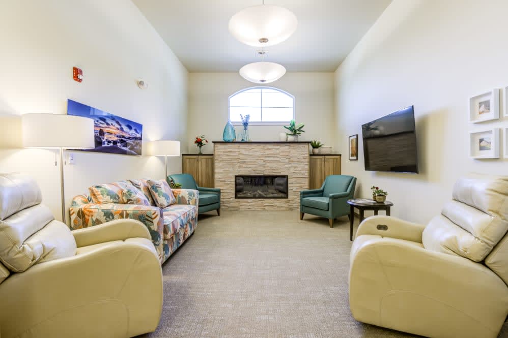 A cozy living room featuring a fireplace, comfortable seating, and a mounted TV.