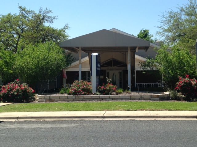 A small building surrounded by greenery seen from across the street.