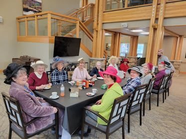 A group of seniors enjoying a gathering at a community center, wearing colorful hats.