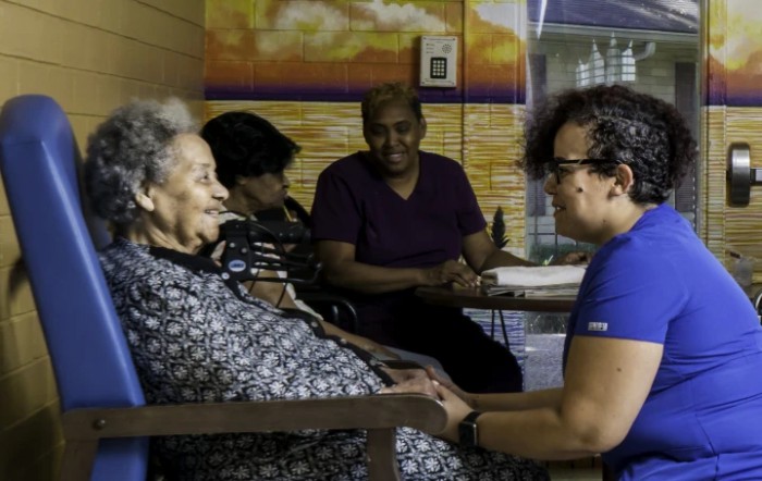 A group of people engaged in conversation at an elderly care facility.
