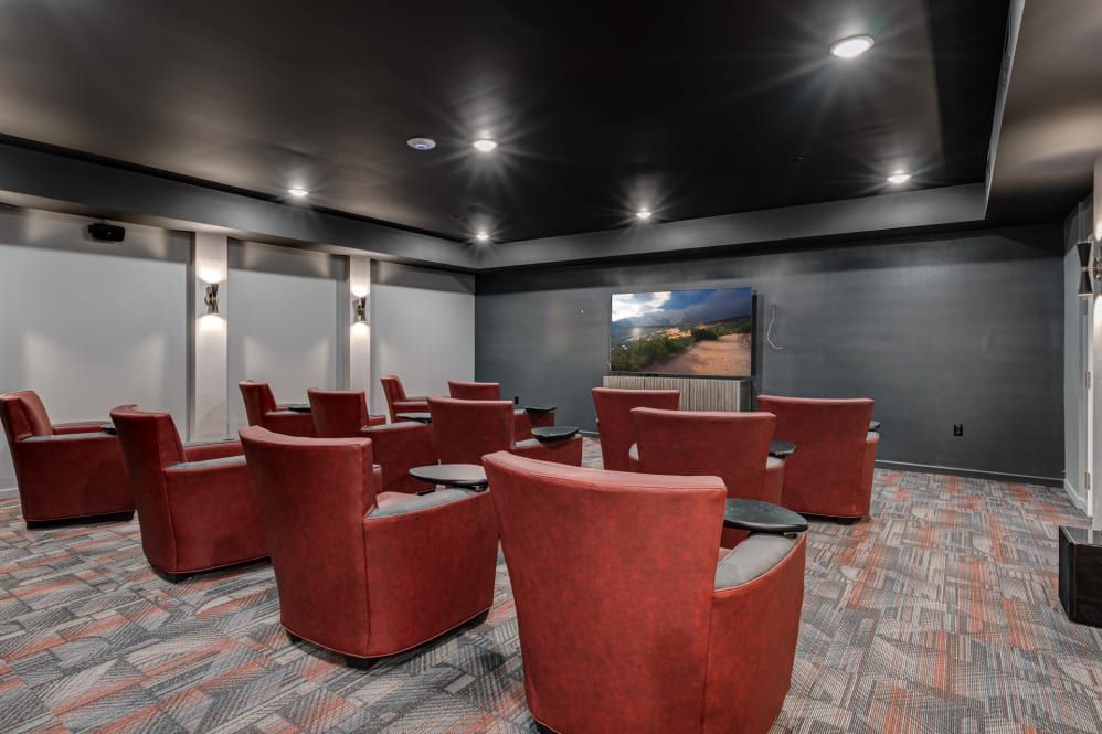 A modern home theater with red swivel chairs facing a large screen.