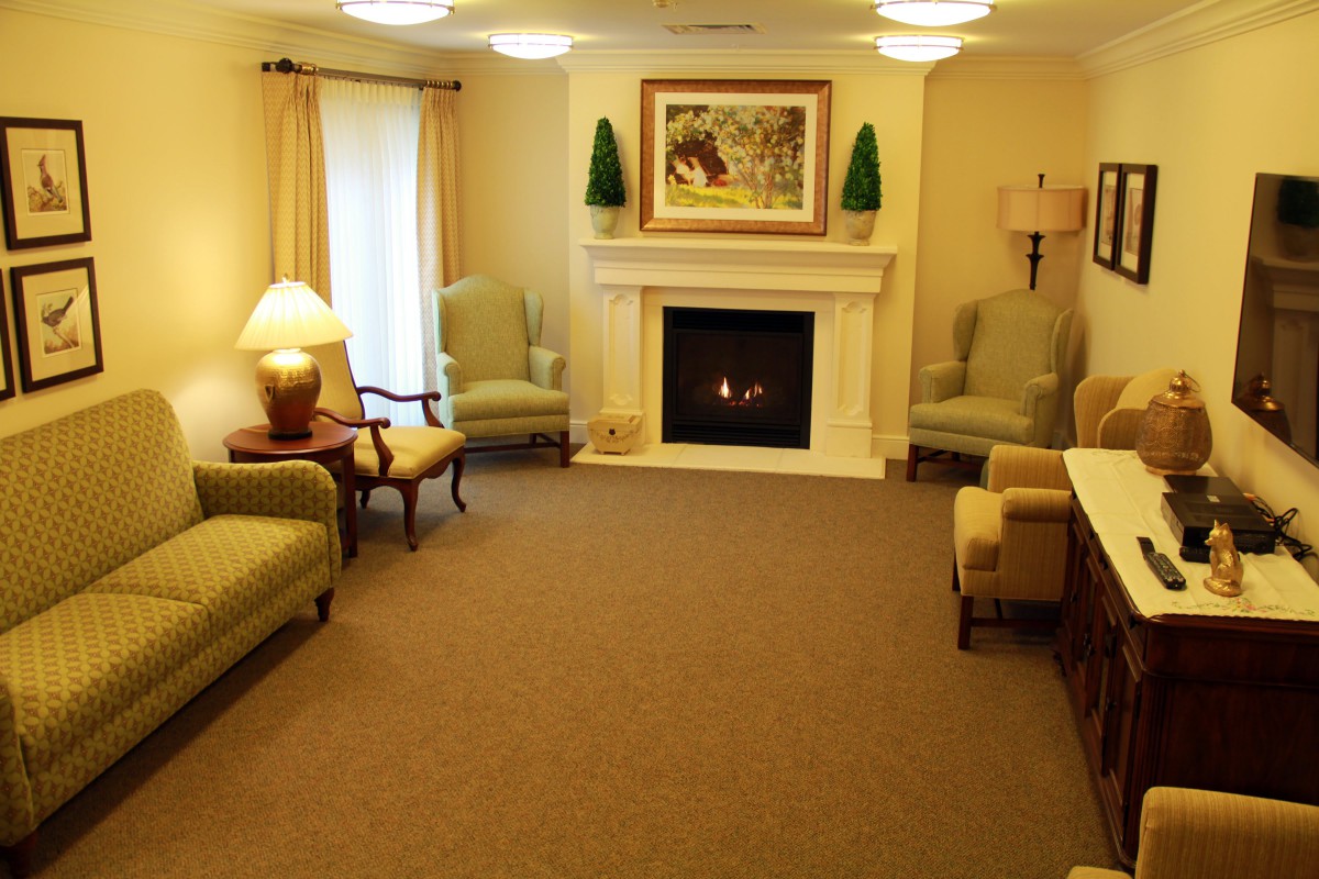 A cozy living room with a fireplace, comfortable seating, and warm lighting.