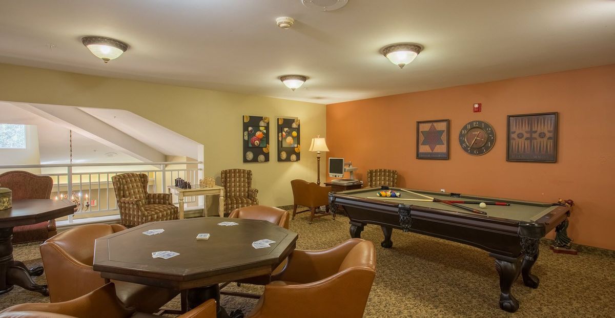 A cozy game room featuring a pool table and a cards table with comfortable seating.