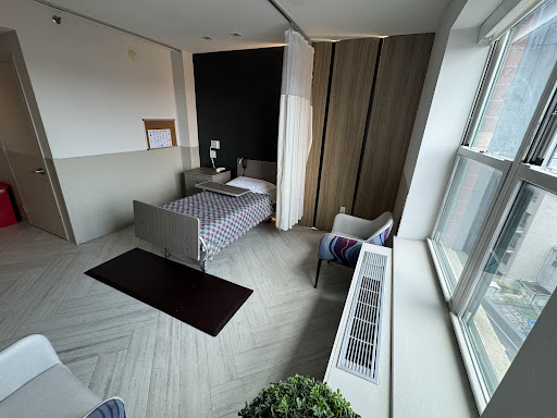 A modern bedroom featuring a bed, chair, and large windows with natural light.