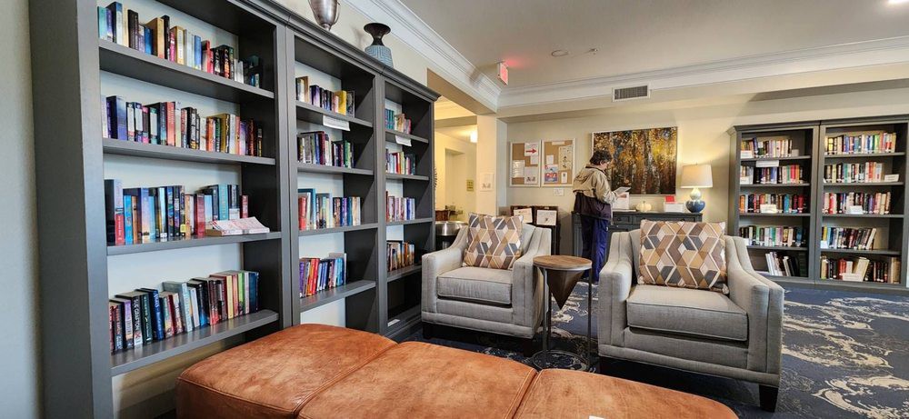 A cozy seating area in a library with bookshelves and armchairs.