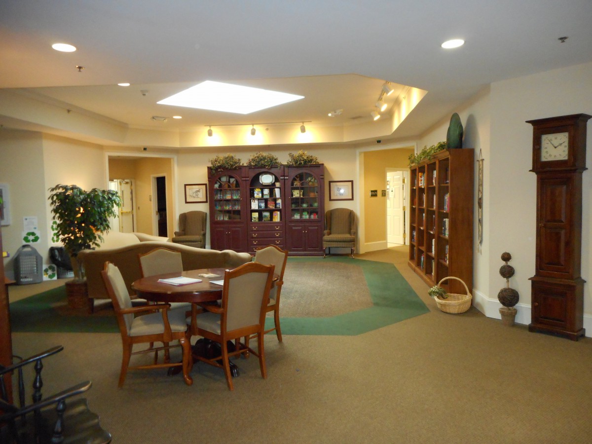 A cozy library setting with bookshelves, a seating area, and a table with chairs.