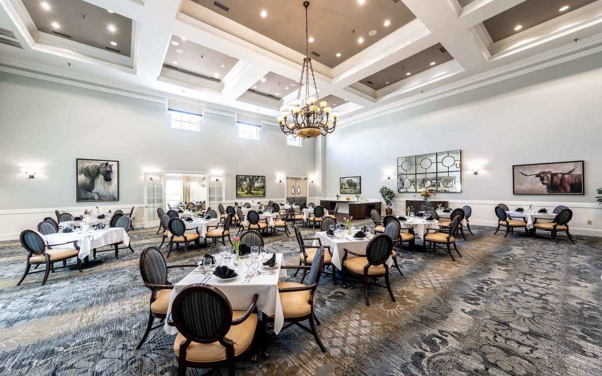 A spacious and elegantly designed dining room with neatly arranged tables and a large chandelier.