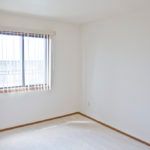 A photo of an empty room with white walls and a window with blinds.