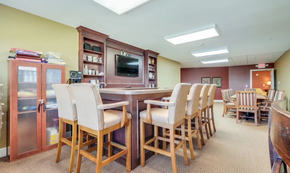 An indoor bar area with high chairs and a television mounted on the wall.