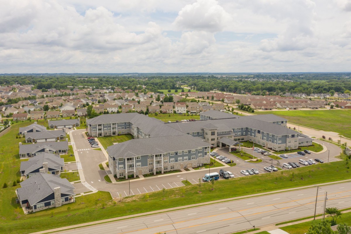 Aerial view of a suburban residential area with large buildings and parking lots under a cloudy sky.