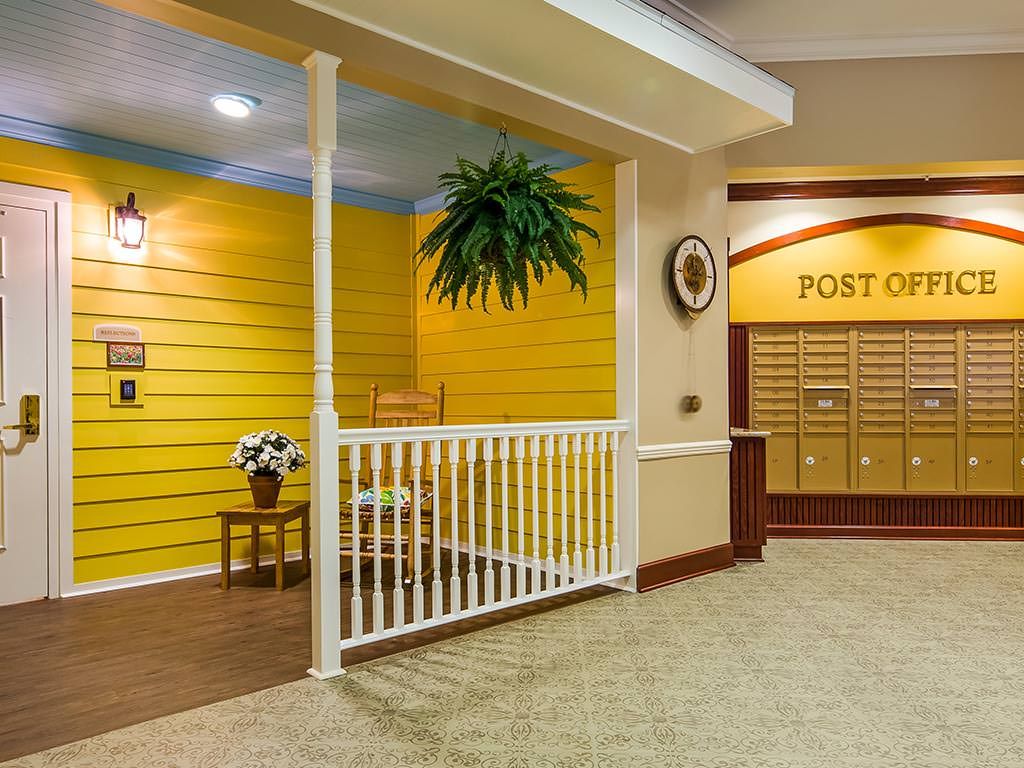 A cozy indoor setting with a post office theme, featuring a seating area with a potted plant and a decorative flower vase.