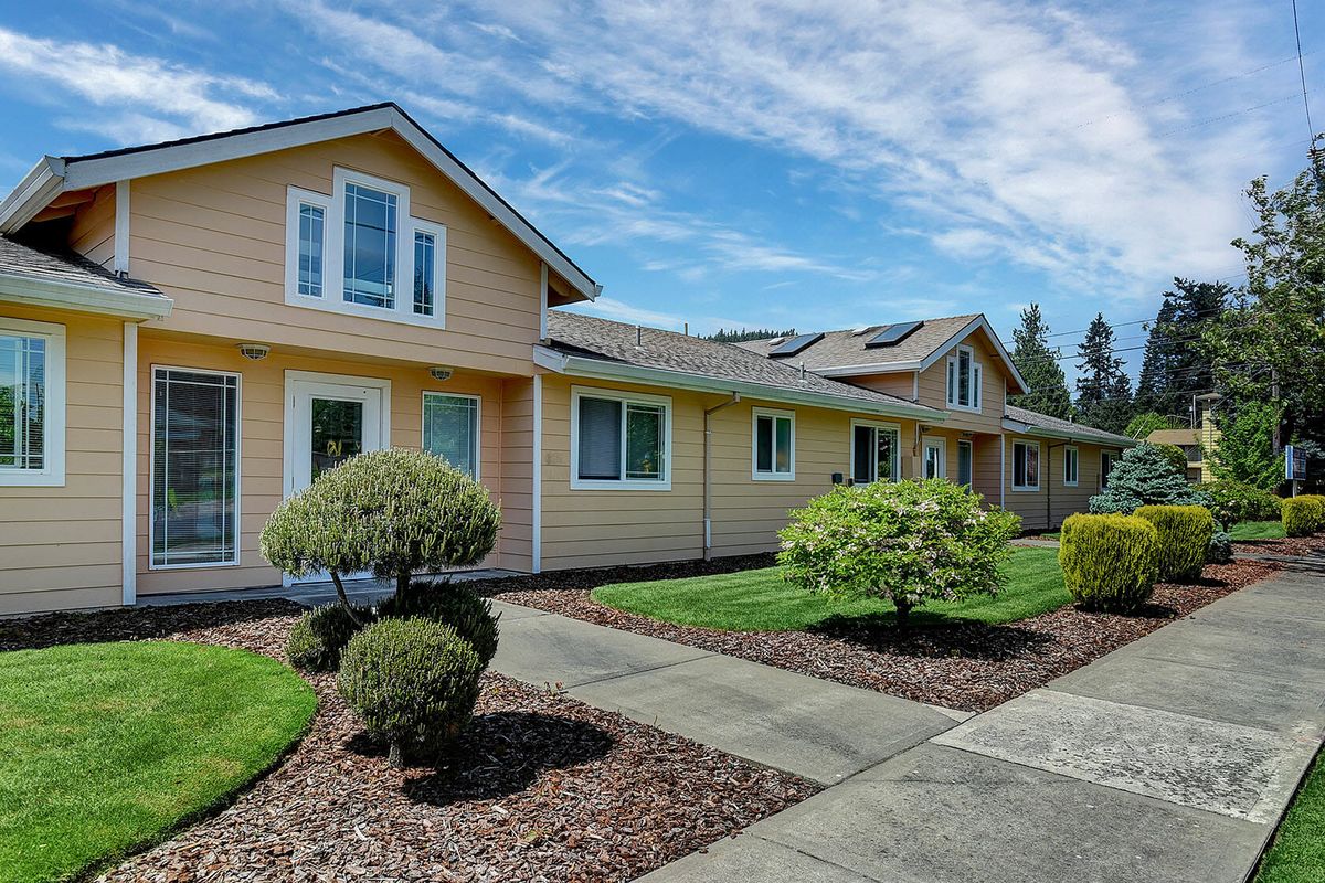 A suburban house with well-maintained landscaping and a clear blue sky.