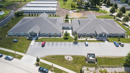 An aerial view of a modern building complex featuring a spacious parking lot and landscaped green areas.