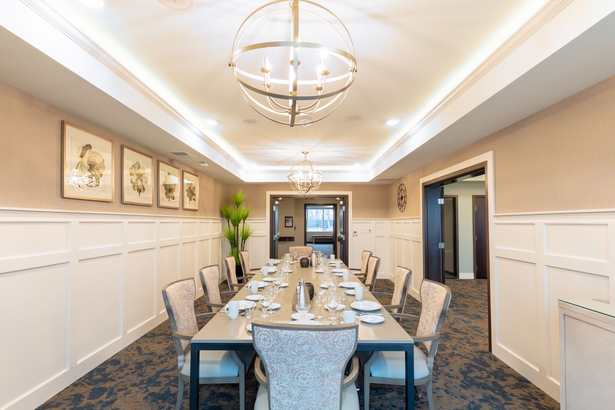 A beautifully decorated dining room with a long table set for a meal, featuring modern lighting and elegant decor.